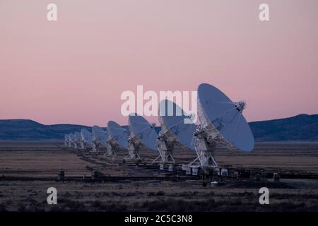 Radio astronomy dishes in pink dusk light as night falls on the Very Large Array (VLA) in New Mexico Stock Photo