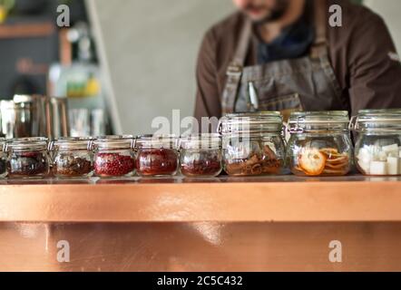 Midsection of barman preparing drinks - herbs and seeds in glass jars Stock Photo