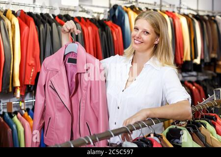 Portrait of nice woman customer with leather jackets in clothes store Stock Photo