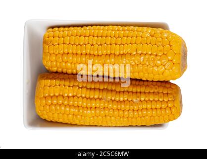 Cobs of freshly boiled corn served on white plate. Tasty vegetarian snack. Isolated over white background Stock Photo