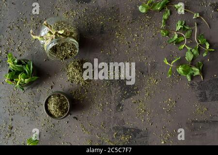 Dried peppermint in a bowl and a bunch of fresh mint, on gray background. Stock Photo