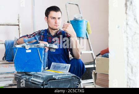 Serious worker repairing room and looking for necessary tool in toolbox Stock Photo