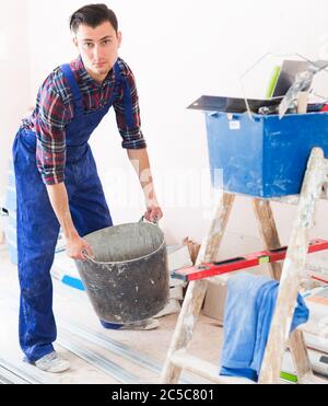 Worker repairing room and looking for necessary tool Stock Photo