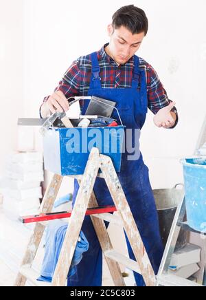 Young attentive builder handyman choosing necessary tool in toolbox Stock Photo