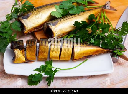 Smoked mackerel cut into pieces with parsley on a table Stock Photo