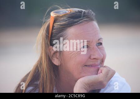 Portrait happy attractive mature woman, laid back and relaxed chin on hand, smiling peaceful confident outdoor, blurred background. Stock Photo