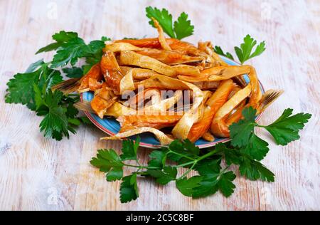 Plate with smoked salmon bellies garnished with fresh greens on wooden background Stock Photo