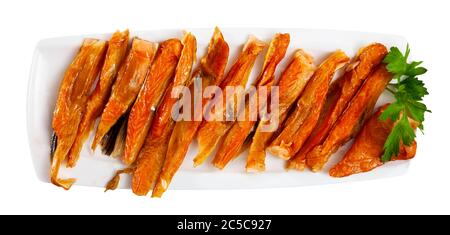 Appetizing smoked salmon belly strips with fresh parsley on plate. Popular fish snack. Isolated over white background Stock Photo