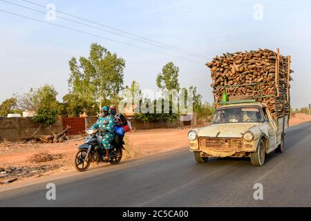 Africa, West Africa, Burkina Faso, Tenkodogo. A car fully loaded with logs overtakes a scooter on a road in eastern Burkina Faso. Stock Photo