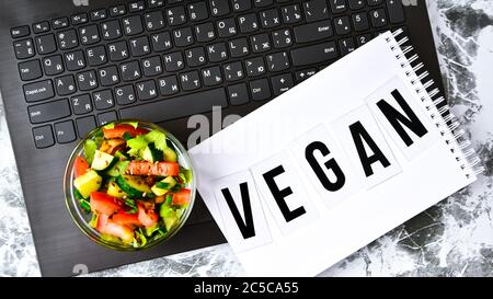 Healthy business lunch snack in office, vegetable salad, VEGAN word on notebook with pen, copy space Stock Photo