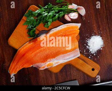 Raw trout fillet lying on wooden table with condiments. Cooking ingredients Stock Photo