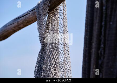Fishing nets hang from a wooden beam. Against a blue sky. Still life and objects. Fishermen, fishing net Stock Photo