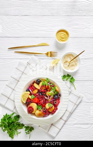 Asian seafood salad of marinated baby octopuses with young potatoes, olive oil, lemon, tomatoes, onions, black olives, sesame seeds with cutlery, on a Stock Photo