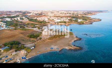 Aerial view of coastline sunset and landmark white washed chapel at Agia Triada beach, Protaras, Famagusta, Cyprus from above. Bird's eye view of tour Stock Photo