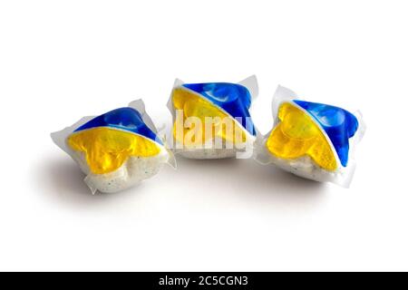 Three blue and yellow dishwasher tablets on isolated white background Stock Photo