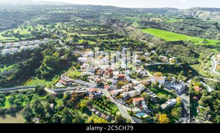 Aerial bird eye view of Goudi village in Polis Chrysochous valley, Paphos, Cyprus. View of traditional ceramic tile roof houses, church, trees, hills Stock Photo