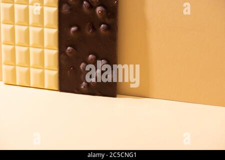 delicious broken white and dark chocolate bars with nuts on beige background Stock Photo