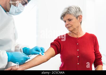 Doctor doing medical injection syringe vaccine to senior patient in hospital for preventing and stop corona virus outbreak Stock Photo