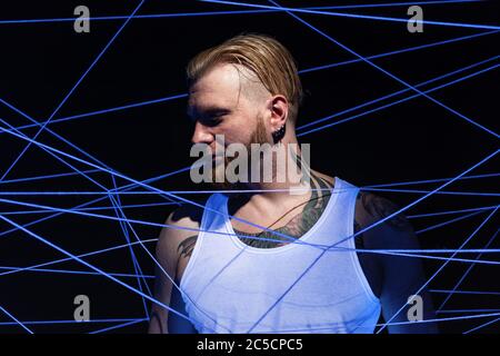 Tattooed man tangled in threads in neon light Stock Photo