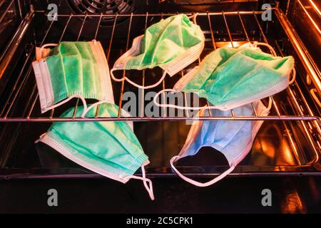 Used everyday masks, mouth-nose protection, are heated in an oven  for 30 minutes at 80 degrees celsius. The virus of Covid-19 cannot withstand heat, but disinfecting the masks in the oven is not safe.   ---   Benutzte Alltagsmasken, Mund-Nasenschutz, werden in einem Backofen bei 80 Grad 30 Minuten lang erhitzt. Die Erreger von Covid-19 ertragen keine Hitze, das Desinfizieren der Masken im Backofen ist allerdings nicht sicher. Stock Photo