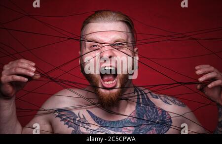 Image of tangled in black threads bearded screaming man Stock Photo
