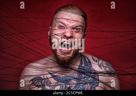 Photo of tangled in black threads bearded man Stock Photo