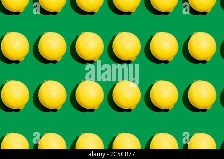 Repeating seamless photo pattern of fresh whole yellow lemons on green background. Food texture. Stock Photo