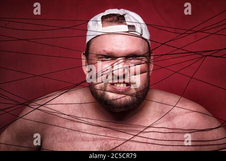 Photo of tangled in black threads fat man Stock Photo