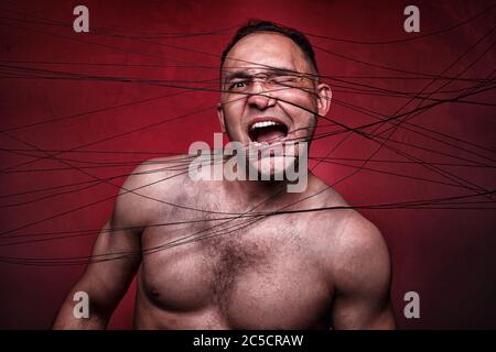 Photo of tangled in black threads muscular man Stock Photo
