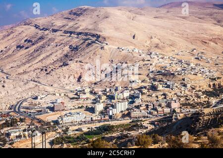 The ancient trade route known as the King's Highway between Aqaba and Petra in Jordan passing above a small settlement. Stock Photo