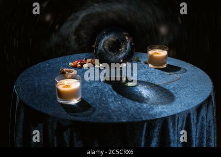Crystal ball near candles and fortune telling stones on dark blue velour cloth on black Stock Photo