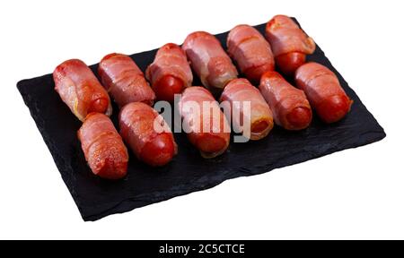 Roasted miniature sausage links wrapped in smoky bacon. Tasty appetizer for wine. Isolated over white background Stock Photo