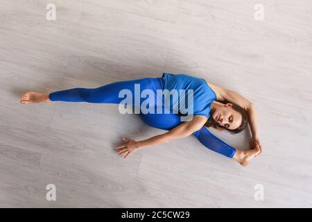 top view of flexible girl stretching while lying on floor Stock Photo -  Alamy