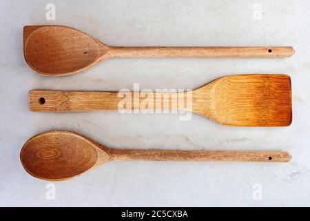Still life image of three wooden kitchen spoons on an off-white marble slab. Stock Photo