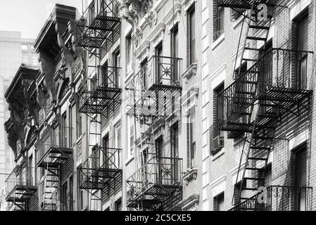 Black and white picture of Manhattan old residential buildings with fire escapes, New York City, USA. Stock Photo