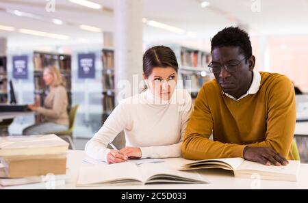 People reading and making notes while preparing for exam in library Stock Photo