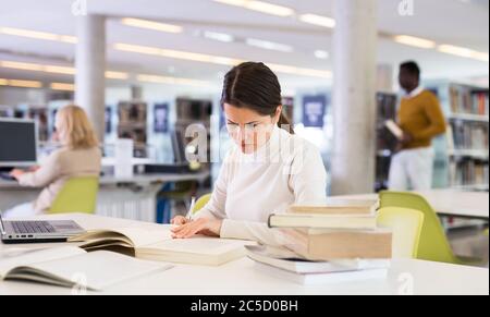 Portrait of upset tired female student preparing for exam in university library Stock Photo