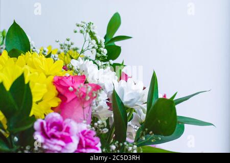 Wedding or holiday bouquet of bright flowers and green leaves. White background. Selective focus, space for text Stock Photo