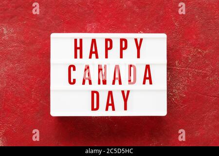 HAPPY CANADA DAY written in light box on red background. Independence day date. Top view, copy space Stock Photo
