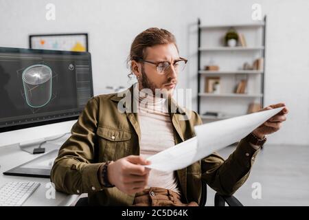 3d artist looking at blueprint while working on project of 3d design in office Stock Photo