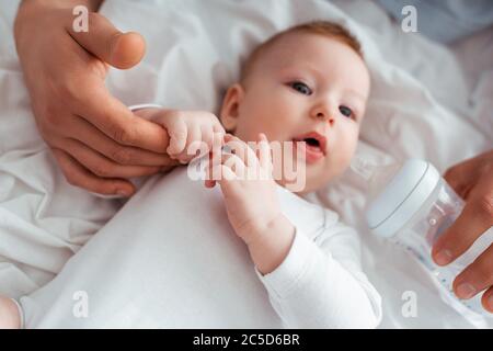 cropped view of man holding baby bottle with milk near adorable son Stock Photo