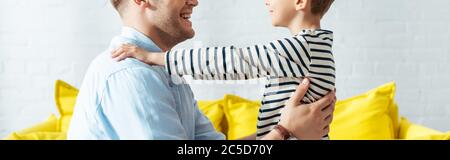 cropped view of boy holding hands on shoulders of smiling father, horizontal image Stock Photo