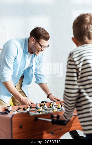 selective focus of cheerful man playing table football with son Stock Photo