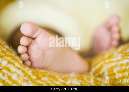 Close-up of little feet of newborn who sleeping in his bed