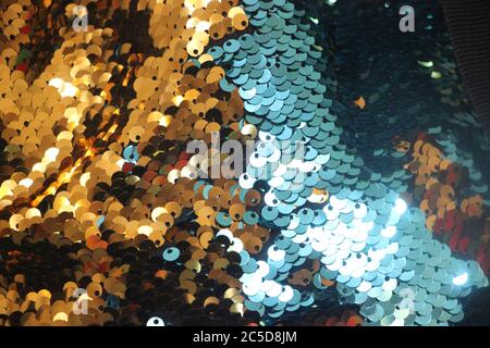 Multicolored shiny sequins. Fabric with sequins as a background. Glittery texture is the trend of the season. Sparkling holographic blue, golden color Stock Photo