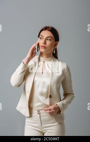 Beautiful businesswoman in formal wear talking on smartphone isolated on grey Stock Photo