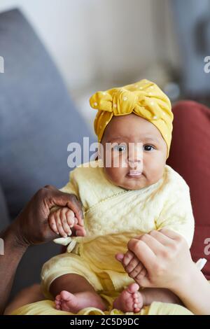Portrait of cute baby girl looking at camera and playing with her parents at home