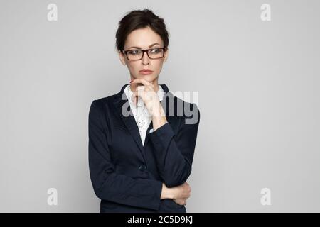 Businesswoman seriosly thinking and holding her hand on chin. Woman wearing eyeglasses looking away. Isolated Stock Photo