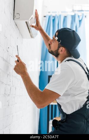 Side view of handyman fixing air conditioner with screwdriver Stock Photo
