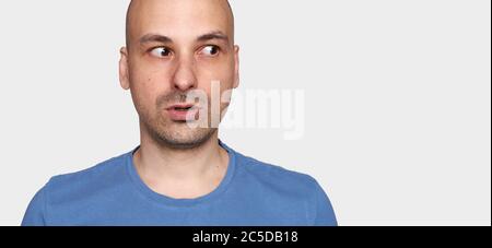 bald man looks away warily. Isolated on grey studio background Stock Photo